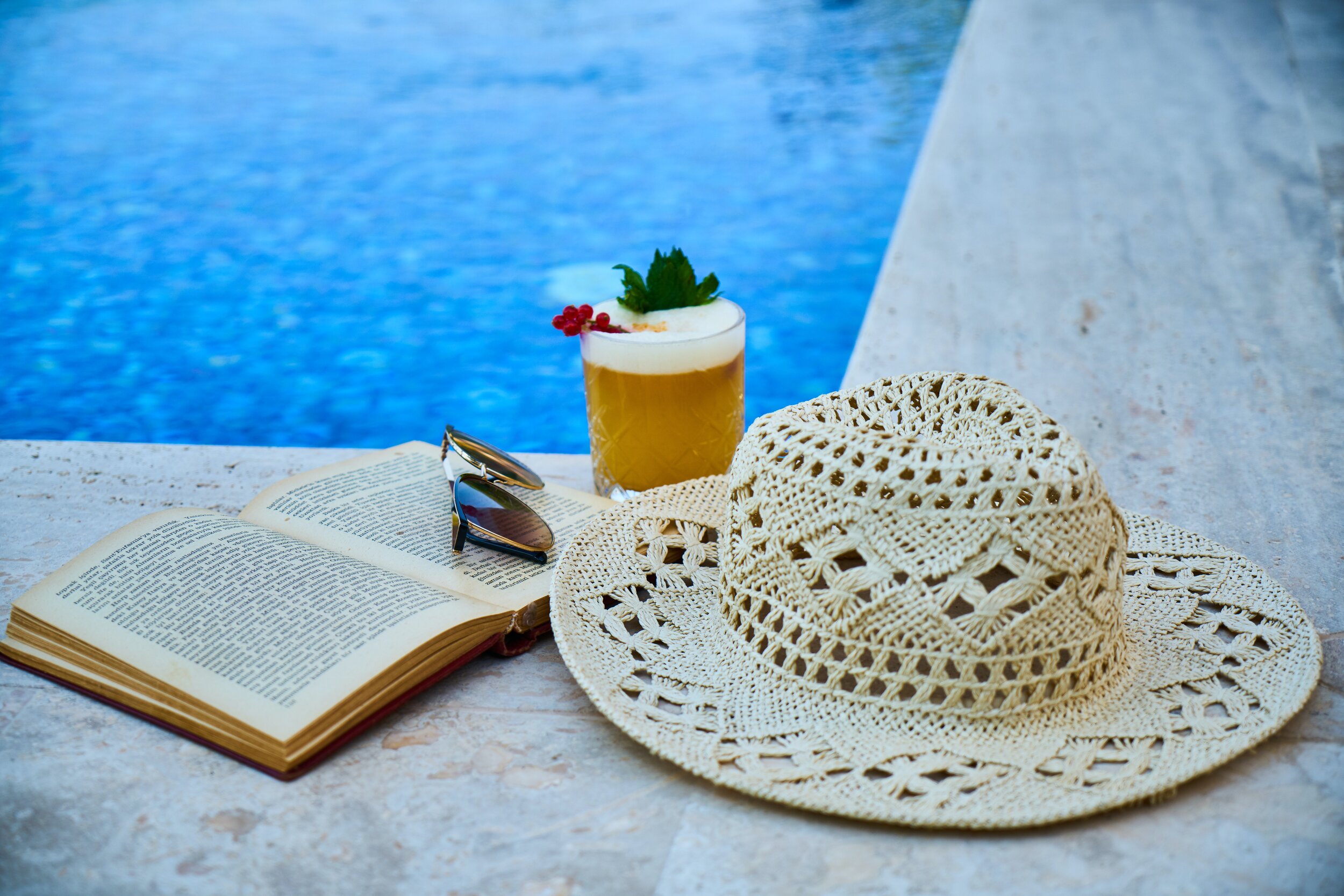 beige-straw-hat-book-sunglasses-and-drink-beside-pool-3019008.jpg
