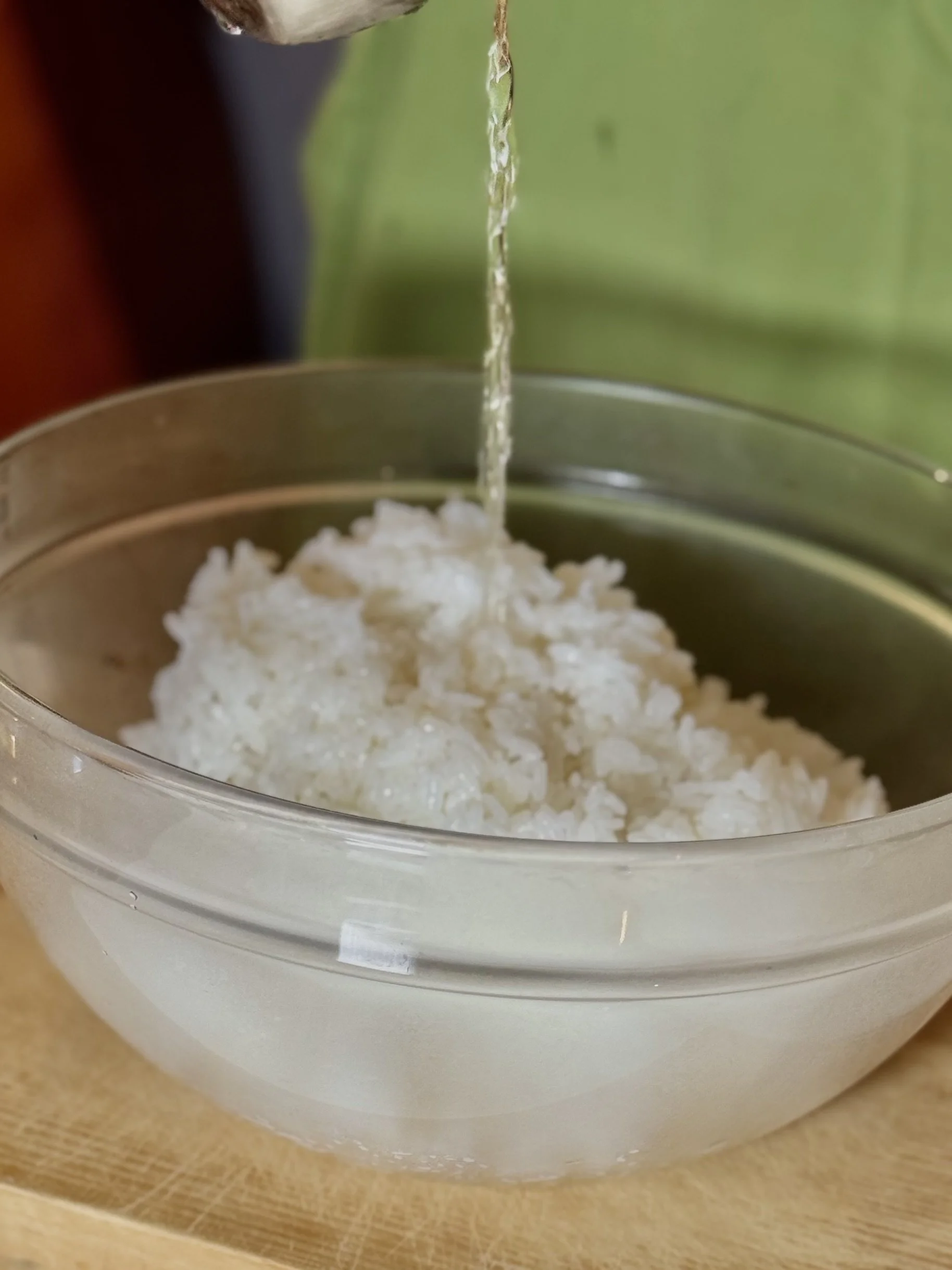 Pouring sushi vinegar over warm Japanese rice to make sushi rice