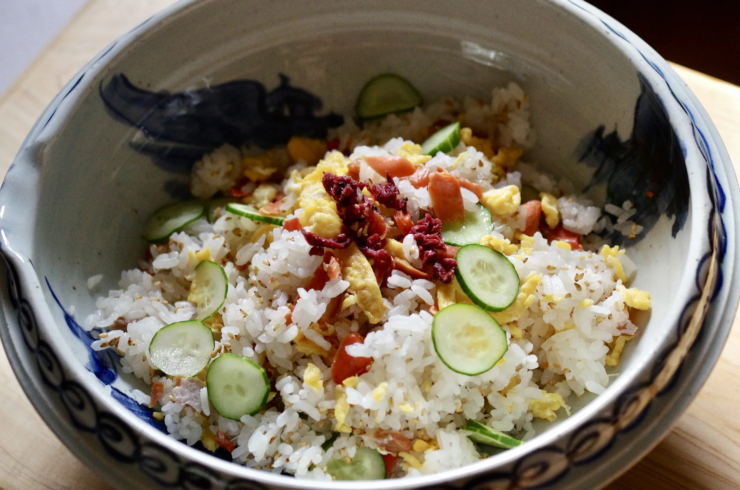 Japanese sushi rice with salmon, egg, cucumber and toasted sesame seeds