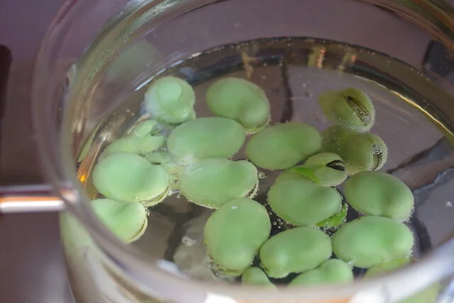Boil fava beans for 10 minutes and remove to strainer.                                  After it gets cold, remove the skin.