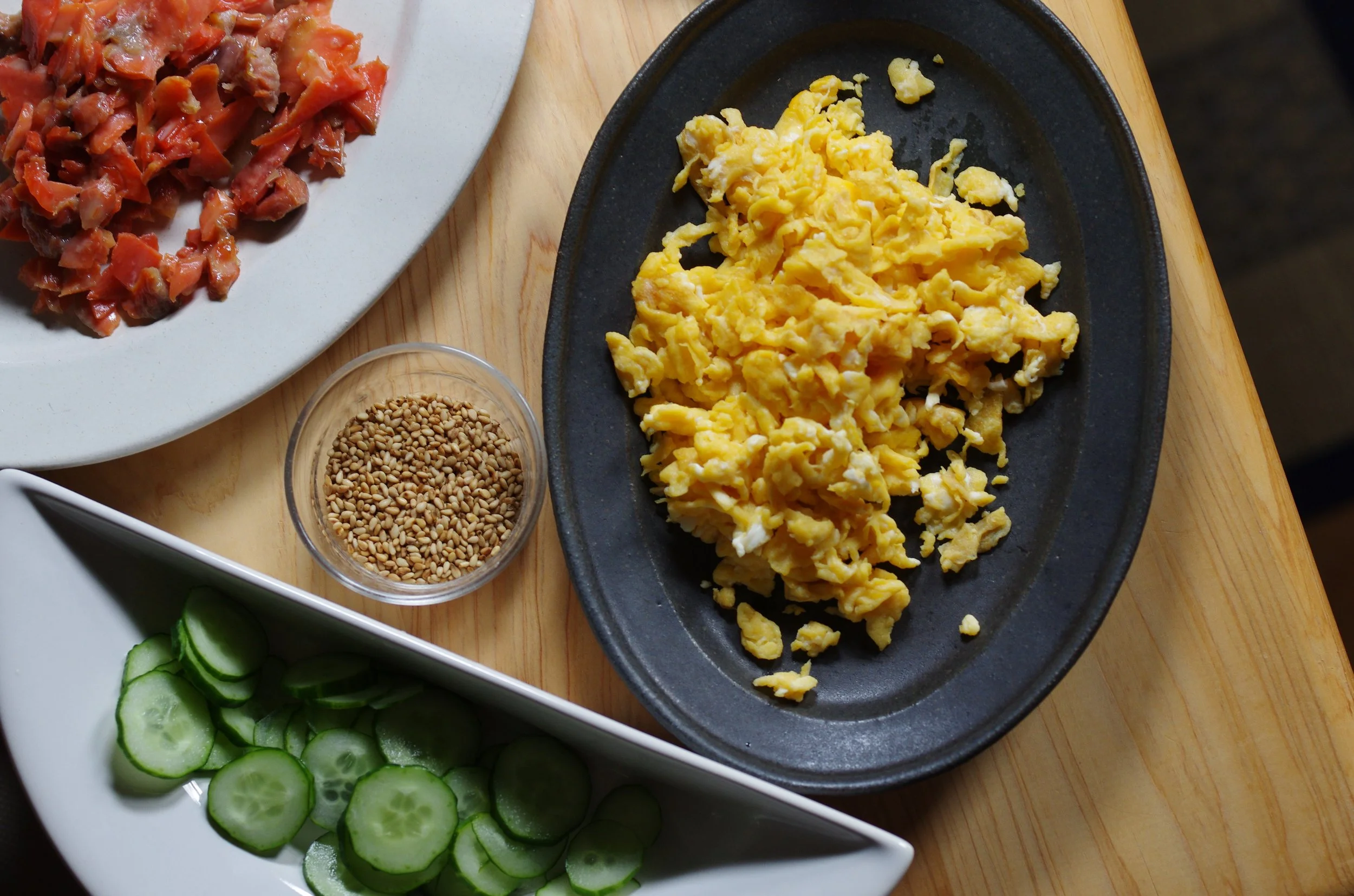 Flaked salmon, soft scrambled egg and sliced cucumber prepared for sushi rice.
