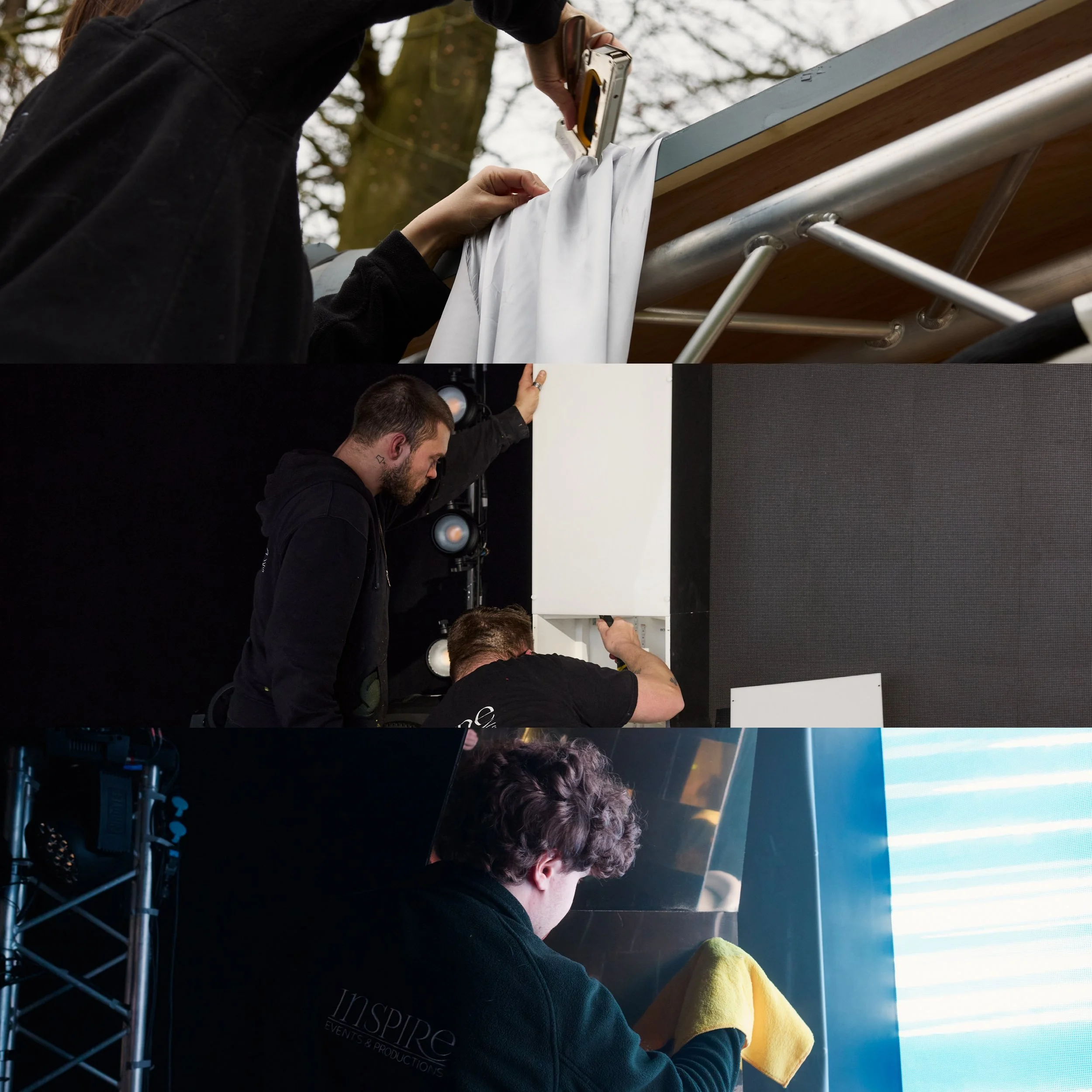 People working together on outdoor stage setup, hanging a white fabric or banner, with trees in the background.