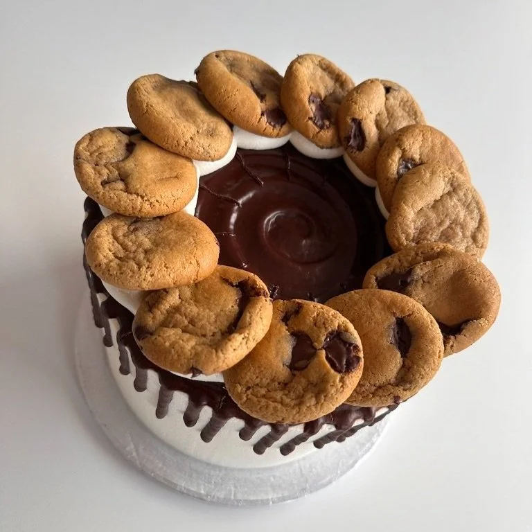 A cake decorated with chocolate cookies and chocolate glaze on top, with chocolate drizzles on the sides.