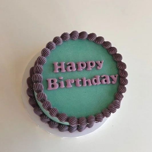 A simple birthday cake with turquoise icing, purple border, and purple "Happy Birthday" text on top.