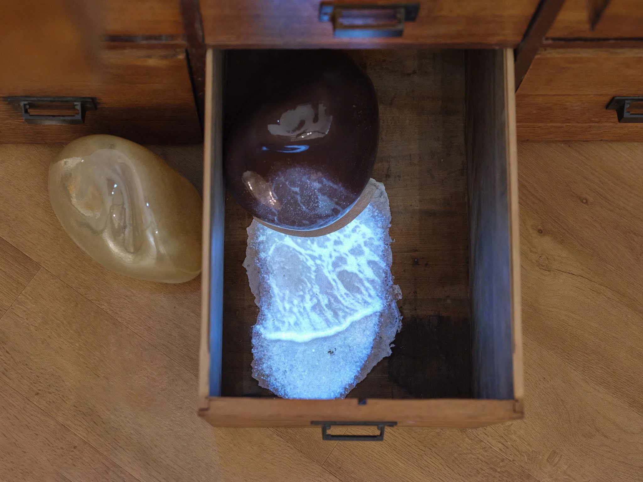 Video projection of waves hitting sand inside drawer. Installation detail from The Day Lasts More Than a Thousand Sunsets by Artist Rae Stern. Photo by T Maxwell Wagner