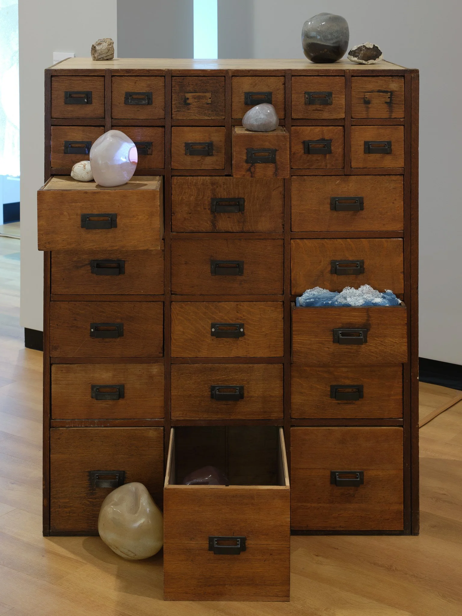 Art installation by Rae Stern. Large antique cabinet with glass, paper, rock and video placed in and around it. Part of the exhibition Afterimage at MoA+L. Photo by T Maxwell Wagner.