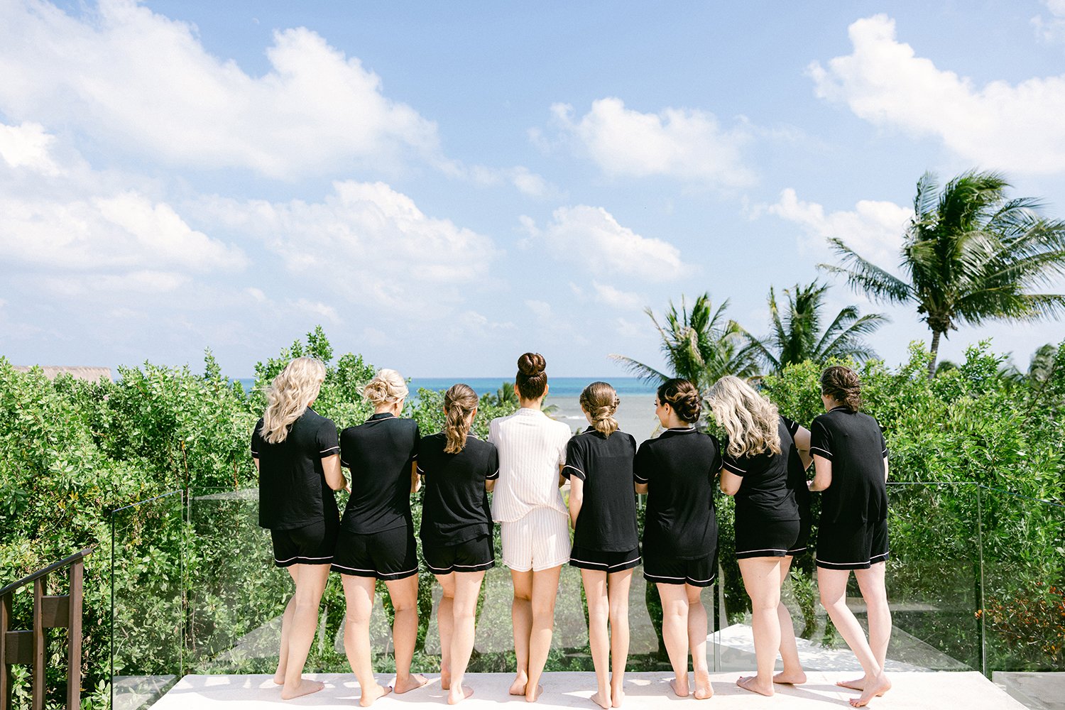 05 bride in white robe and her bridesmaids looking to the horizon ocean view surrounded by green tropical plants at Rosewood Mayakoba Riviera Maya Cancun Mexico.JPG