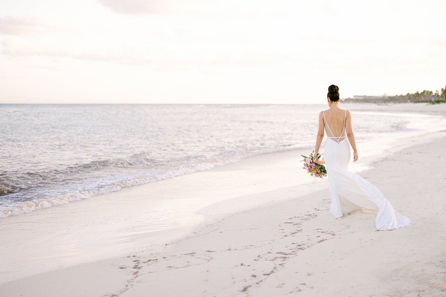 35 wonderful landscape photography of bride walking on the beach wearing her white wedding dress and holdin bouquet of flowers at Rosewood Mayakoba Riviera Maya Cancun Mexico.JPG