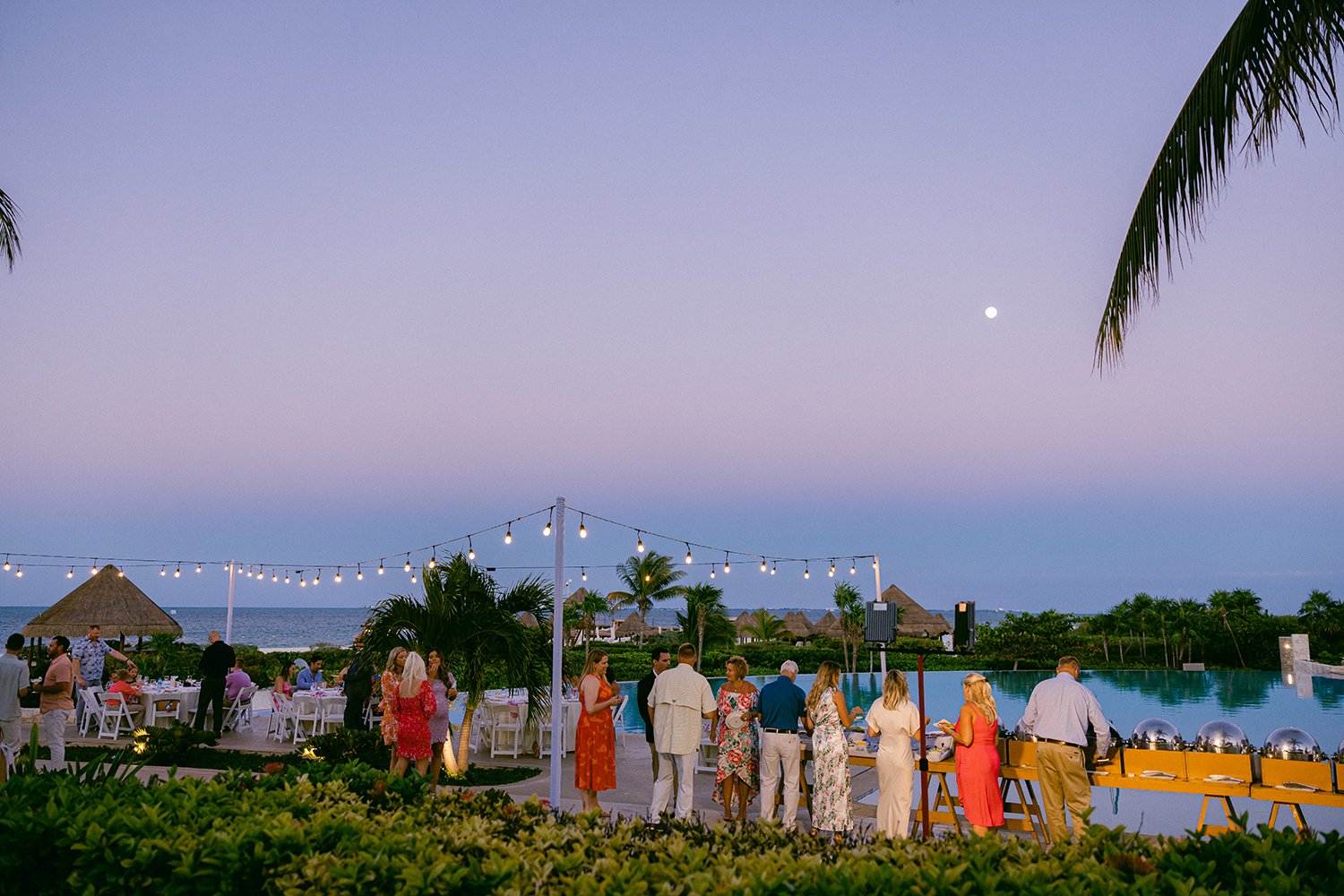 13 Rehearsal dinner guests enjoy the weather and serve themselves from the buffet with ocean views of the purple sunset behind at Dreams Riviera Cancun Mexico.JPG