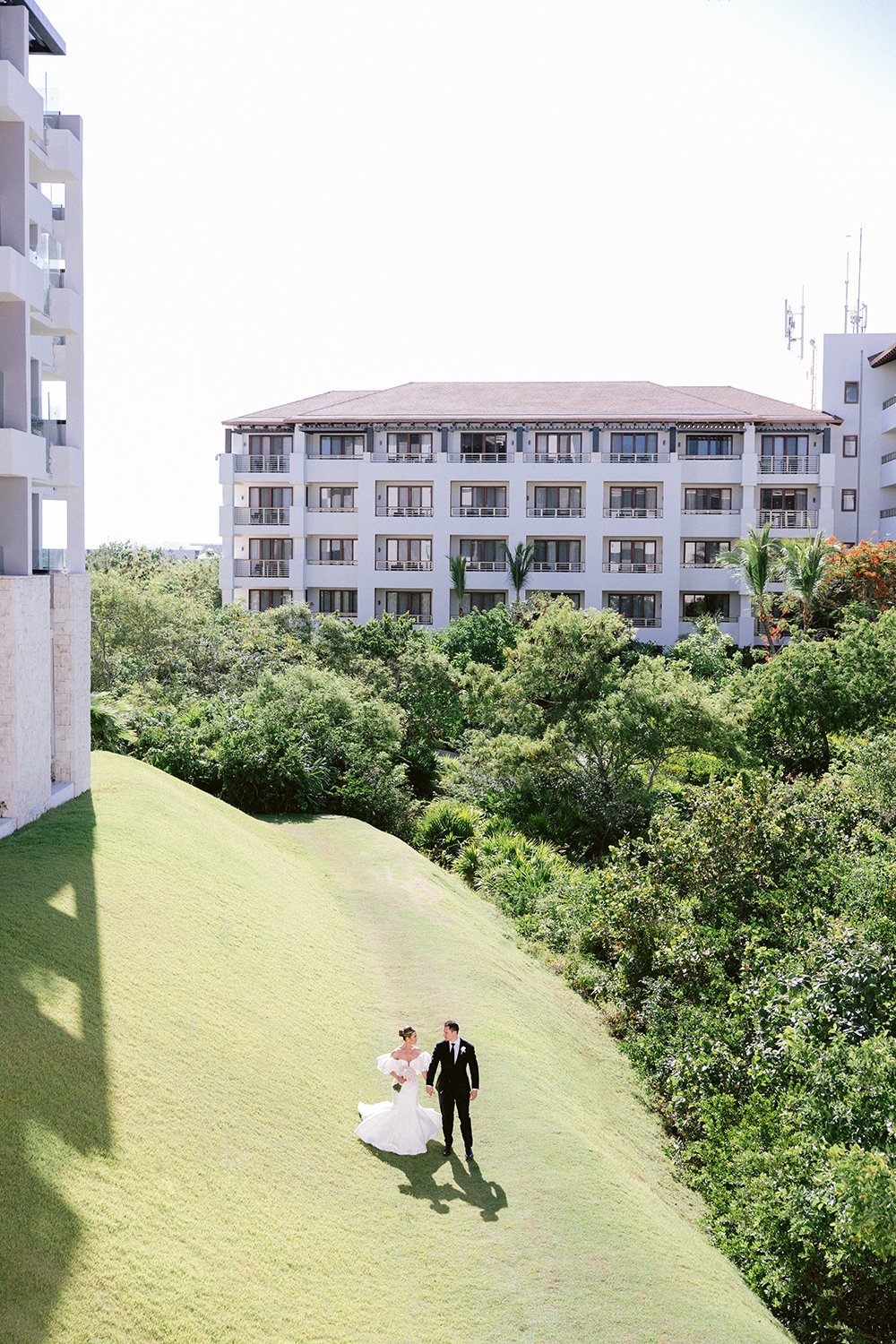29 amazing wide photography of bride and groom walking forward directly to wedding ceremony over clean grass landscape with the hotel behind at Dreams Riviera Cancun.JPG
