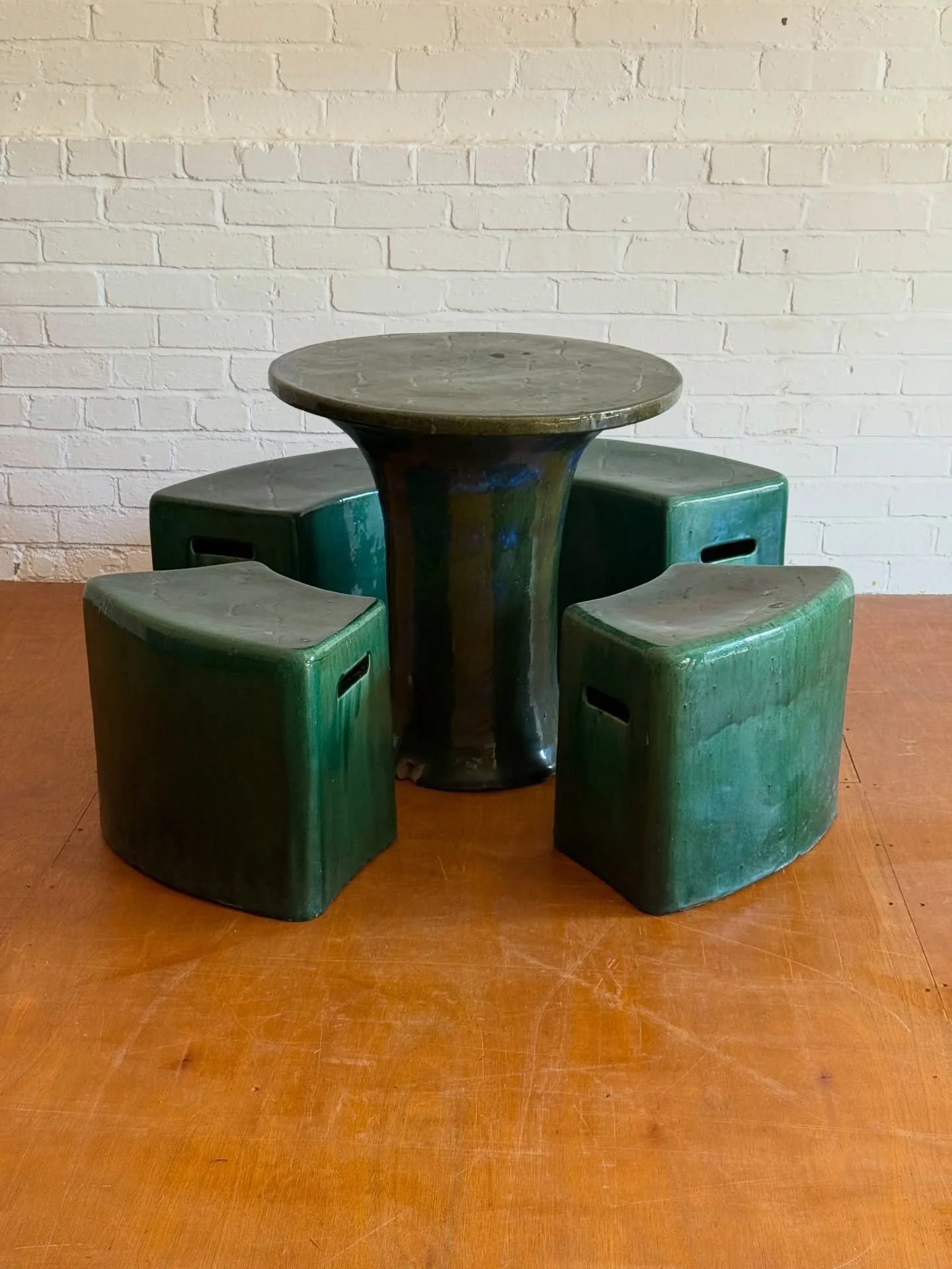 A striking and highly sculptural ceramic table and stools set, featuring a central pedestal table with four matching seats, all finished in a richly variated deep green glaze. Attributed to Paola Navone Inout design for Gervasoni 1882 although likely