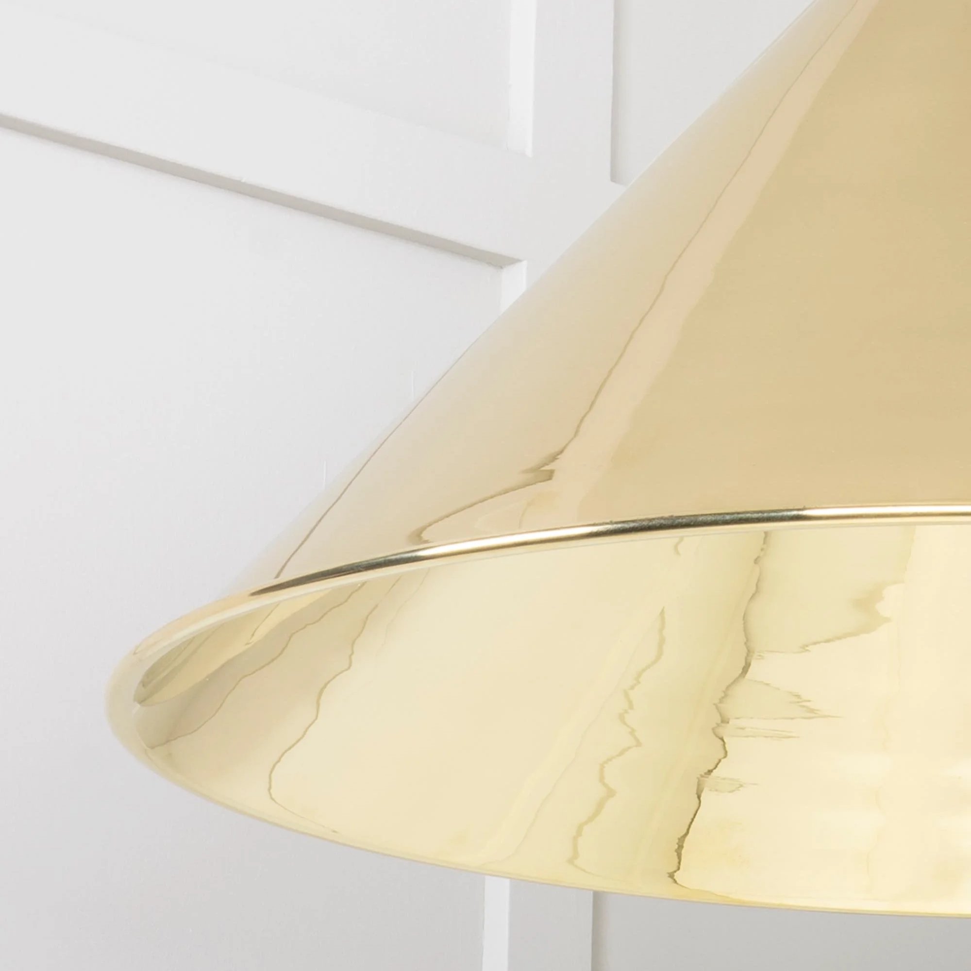 Close-up of the Hawthorne brass pendant lamp showing hand-polished finish and warm reflective glow