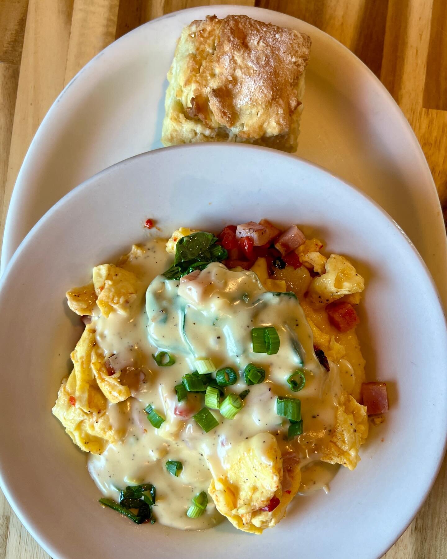 Top of the morning to y&rsquo;all! Today we are tempting you with a two egg scramble with Canadian bacon, spinach, roasted garlic, and roasted red bell peppers served over potato cakes or cheese grits and then topped with a cheddar cheese sauce and g