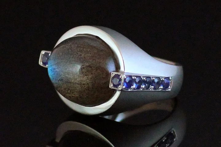 This client had just purchased a labradorite cabochon stone and she wanted a unique design for herself. She asked me to make her a ring and she also had exquisite blue sapphires which accentuated the blue tones in the labradorite. Being a purist the 
