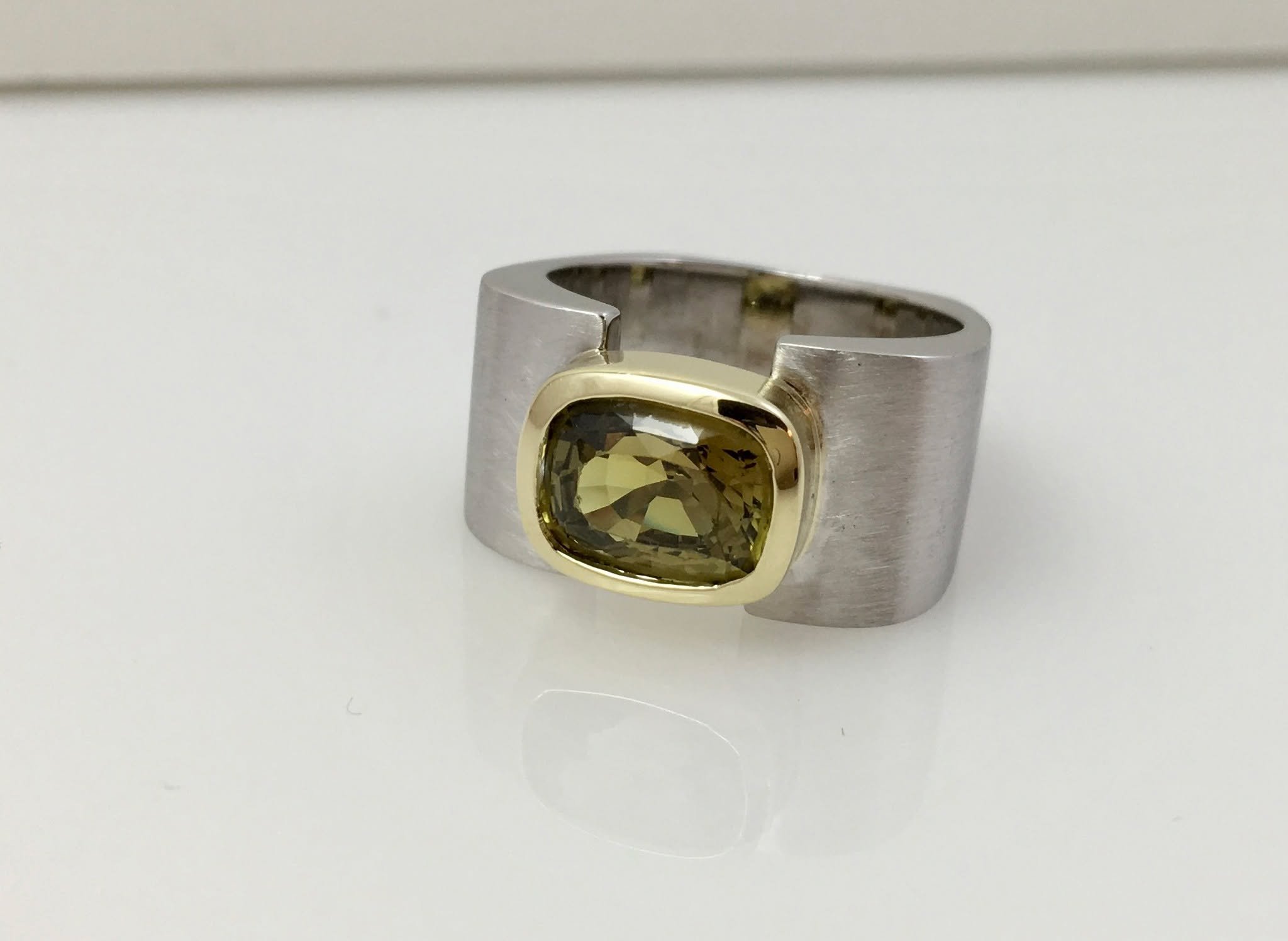 Custom design for client's cushion cut tourmaline set in a yellow gold bezel with a curved band in white gold.  I love the contrast and the unusual color and the bold design for an engagement ring. 

#customjewelrydesign #contemporaryjewelry #uniquee