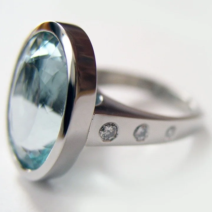 Gorgeous oval aquamarine bezel set in white gold with diamond accents on the side.  This design can be modified for almost any shape of gemstone as well as the accent stones.  The possibilities are endless! 

#aquamarinejewelry #ovalaquamarinering #c