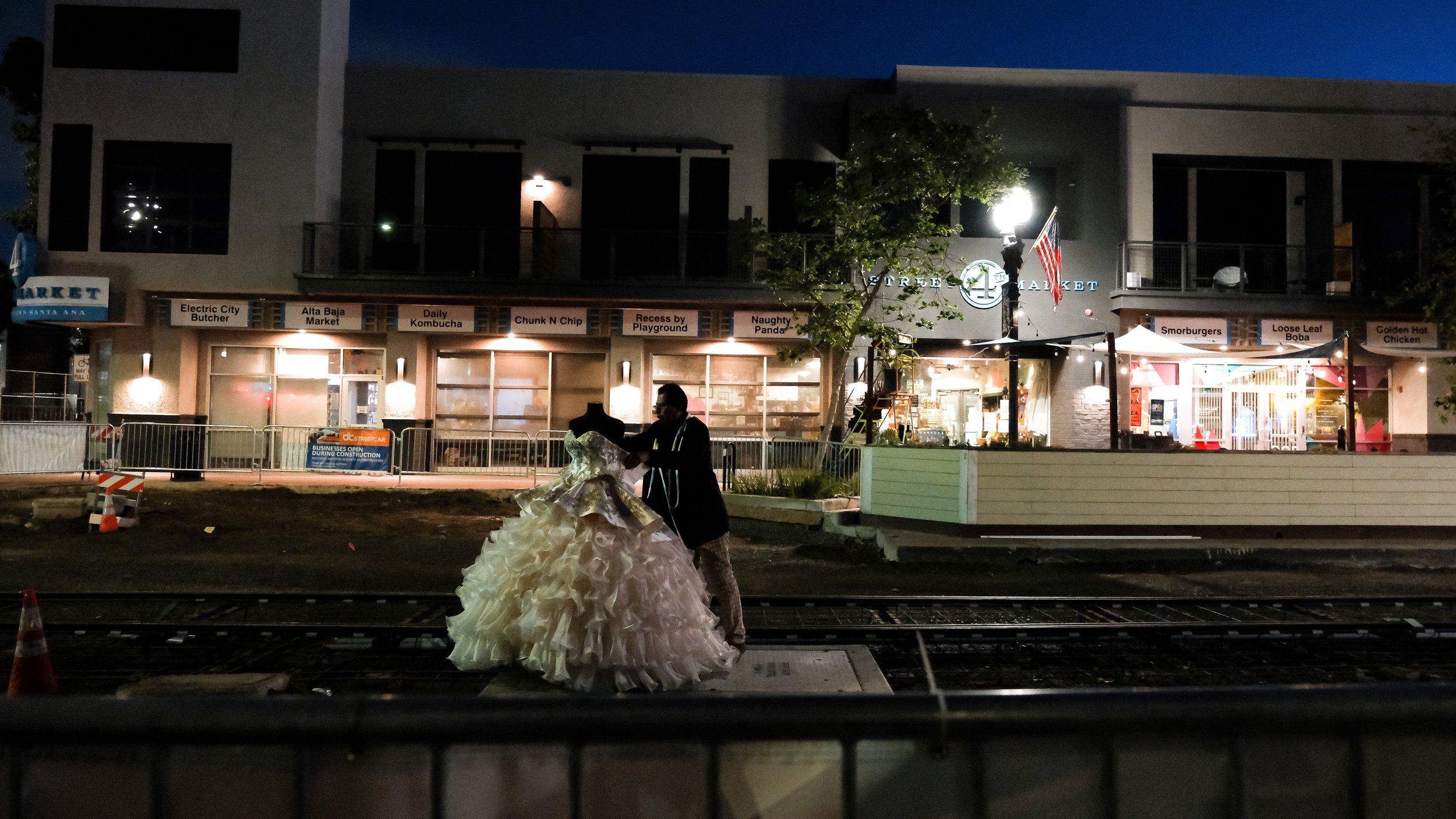 Valentín Martinez, owner of Nino's Bridal Couture, sets up a quinceañera dress display at the center of the Orange County Streetcar construction site on Fourth Street in downtown Santa Ana at around 6:15 a.m. Martinez is one of many business owners d