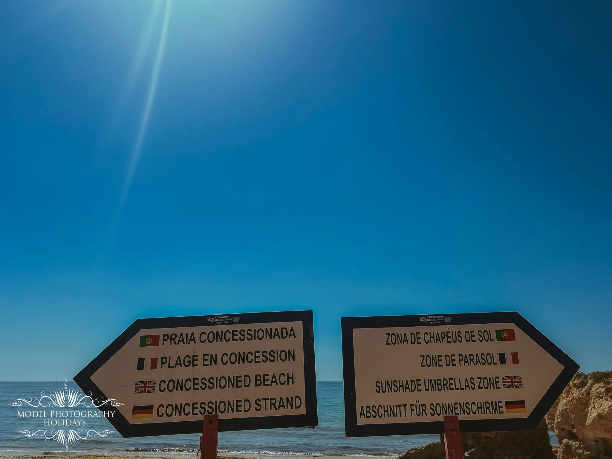 Beach concession signs with translations in multiple languages, including English, Portuguese, Spanish, German, and French, indicating areas like the sunscreen zone, sunshade umbrellas zone, and concession beach.