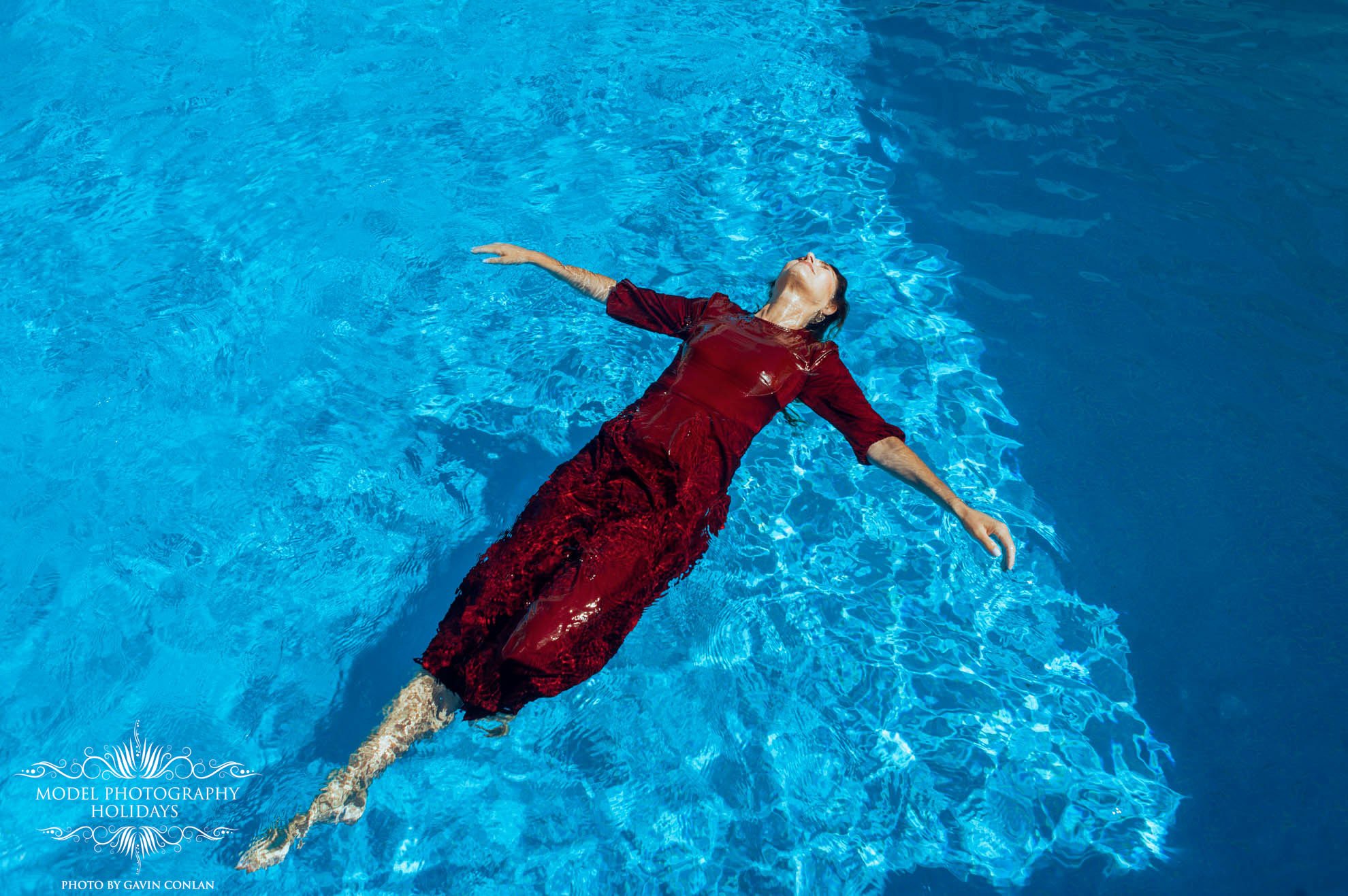 Person in red dress floating in a swimming pool.