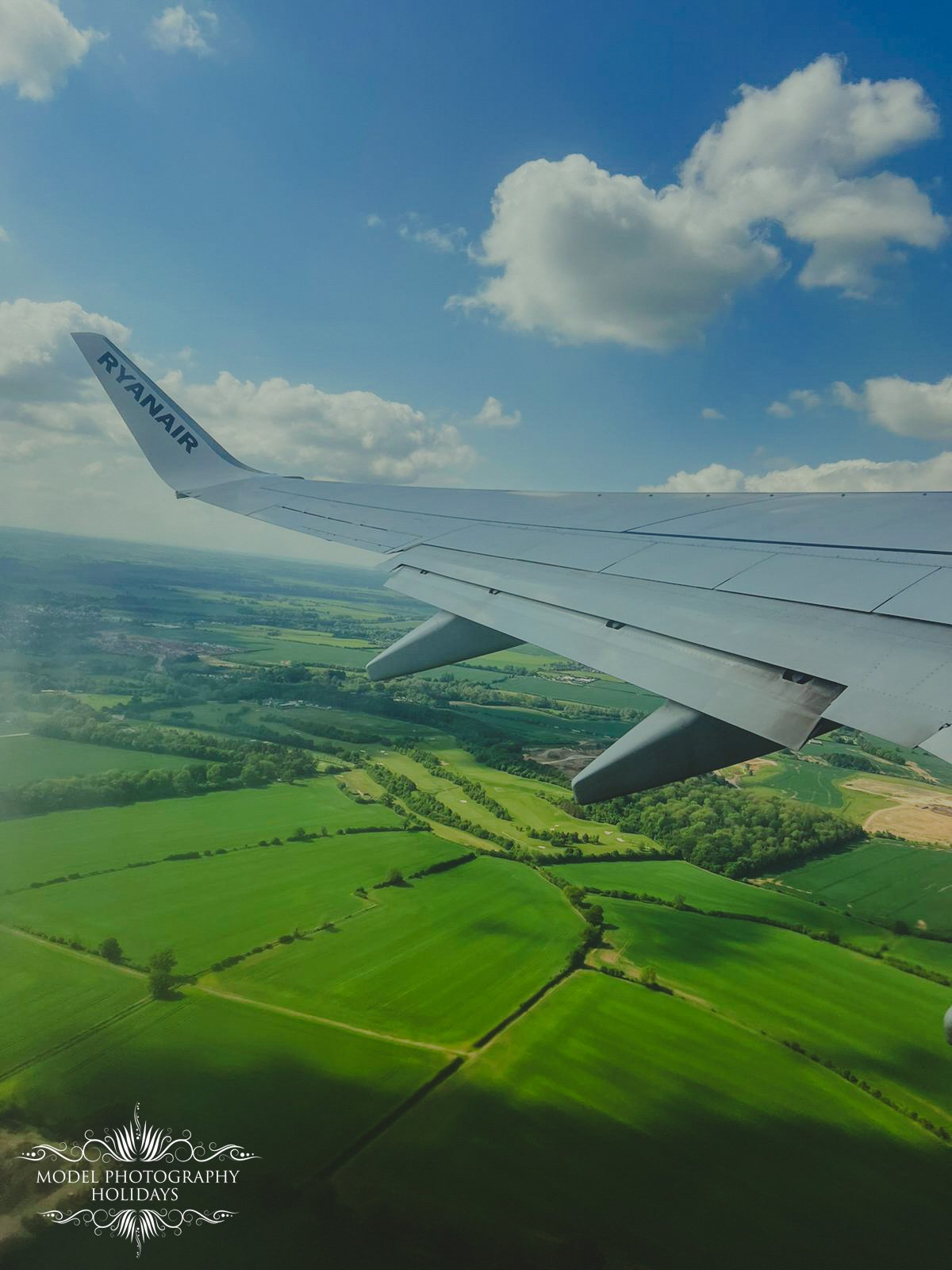 Airplane wing over green fields