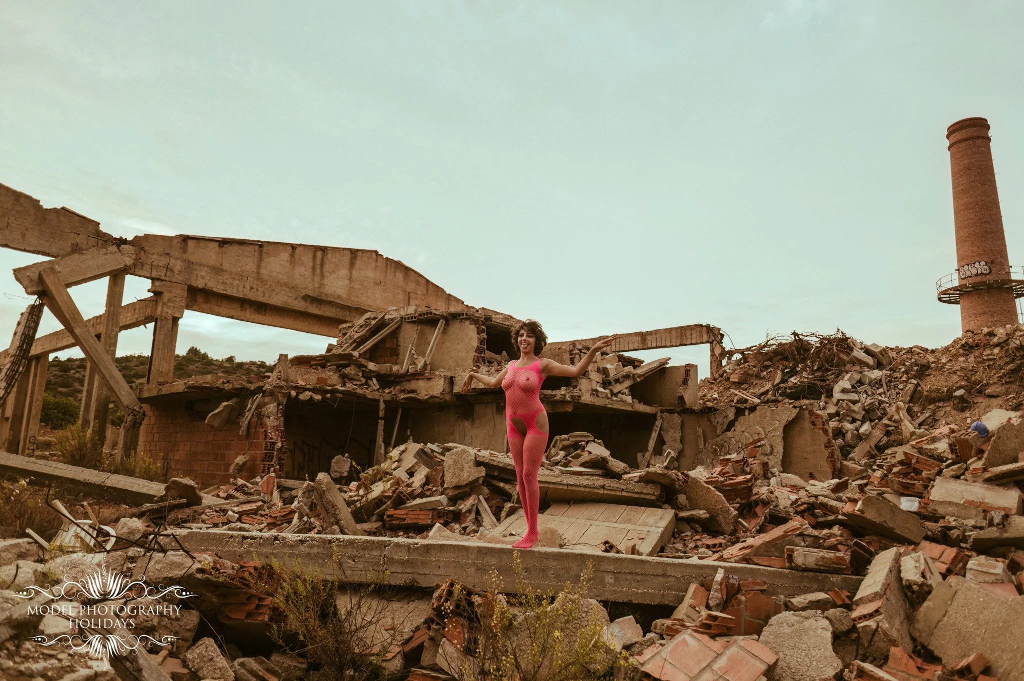 A woman in a pink fishnet outfit standing amidst the rubble and destruction of a collapsed building with a chimney in the background.