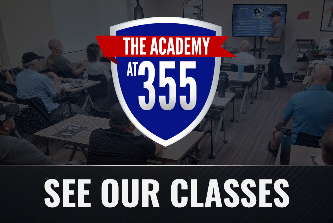 A classroom or seminar room with people seated at tables, a presenter standing next to a large screen, and a banner or overlay displaying 'The Academy at 355' and 'See Our Classes.'