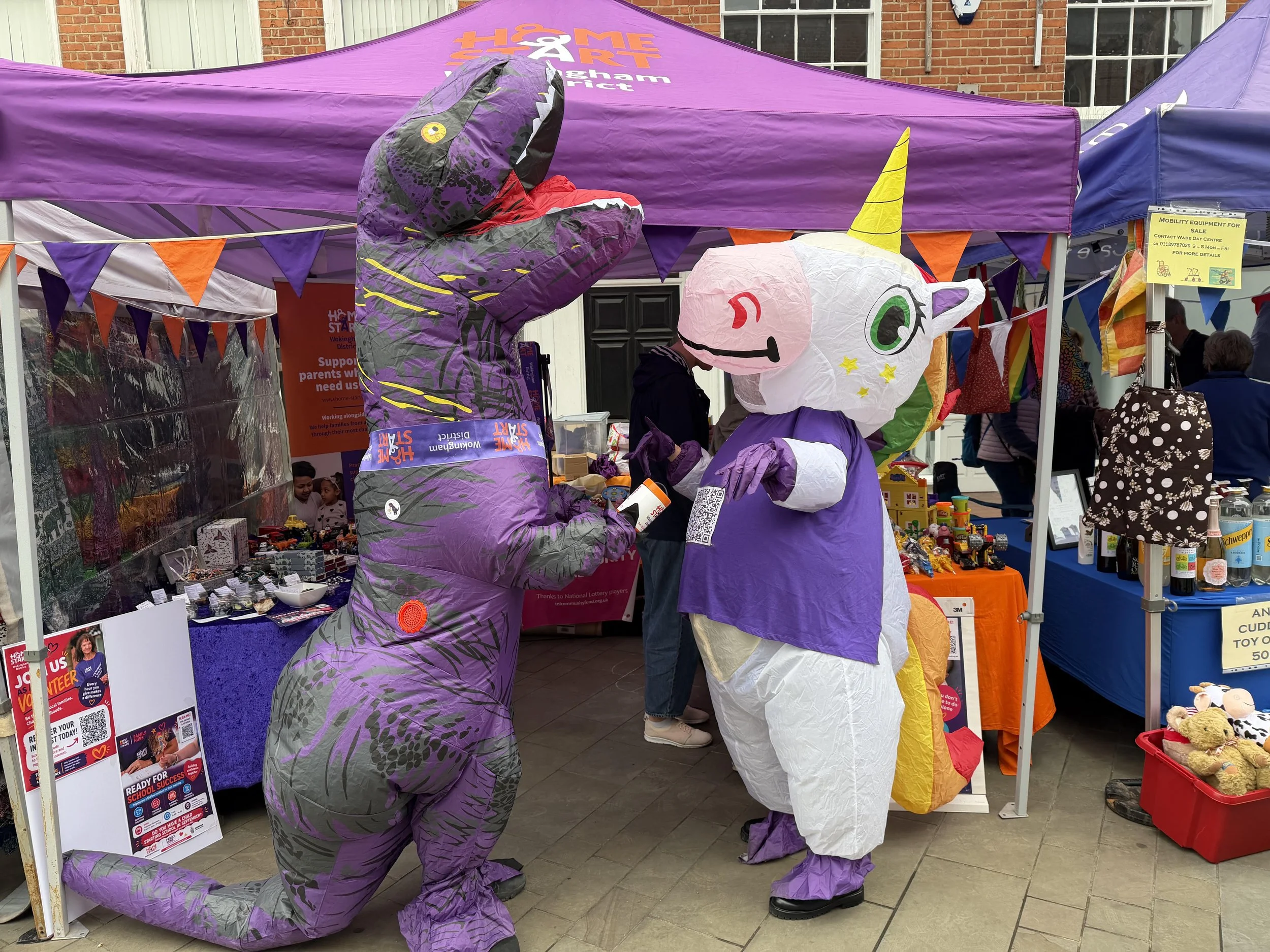 Home-Start Dino and Unicorn Mascots in front of purple gazebo