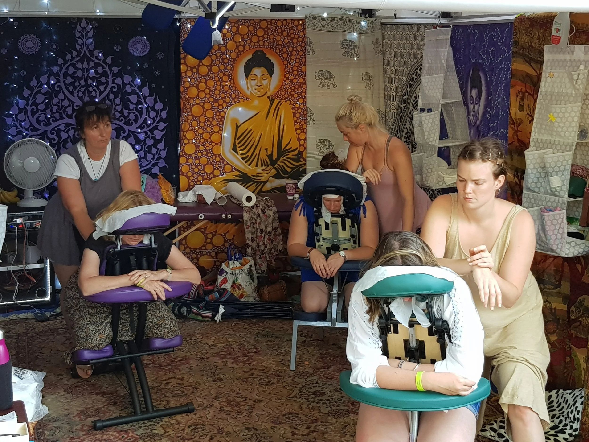People receiving massage in a decorated festival gazebo