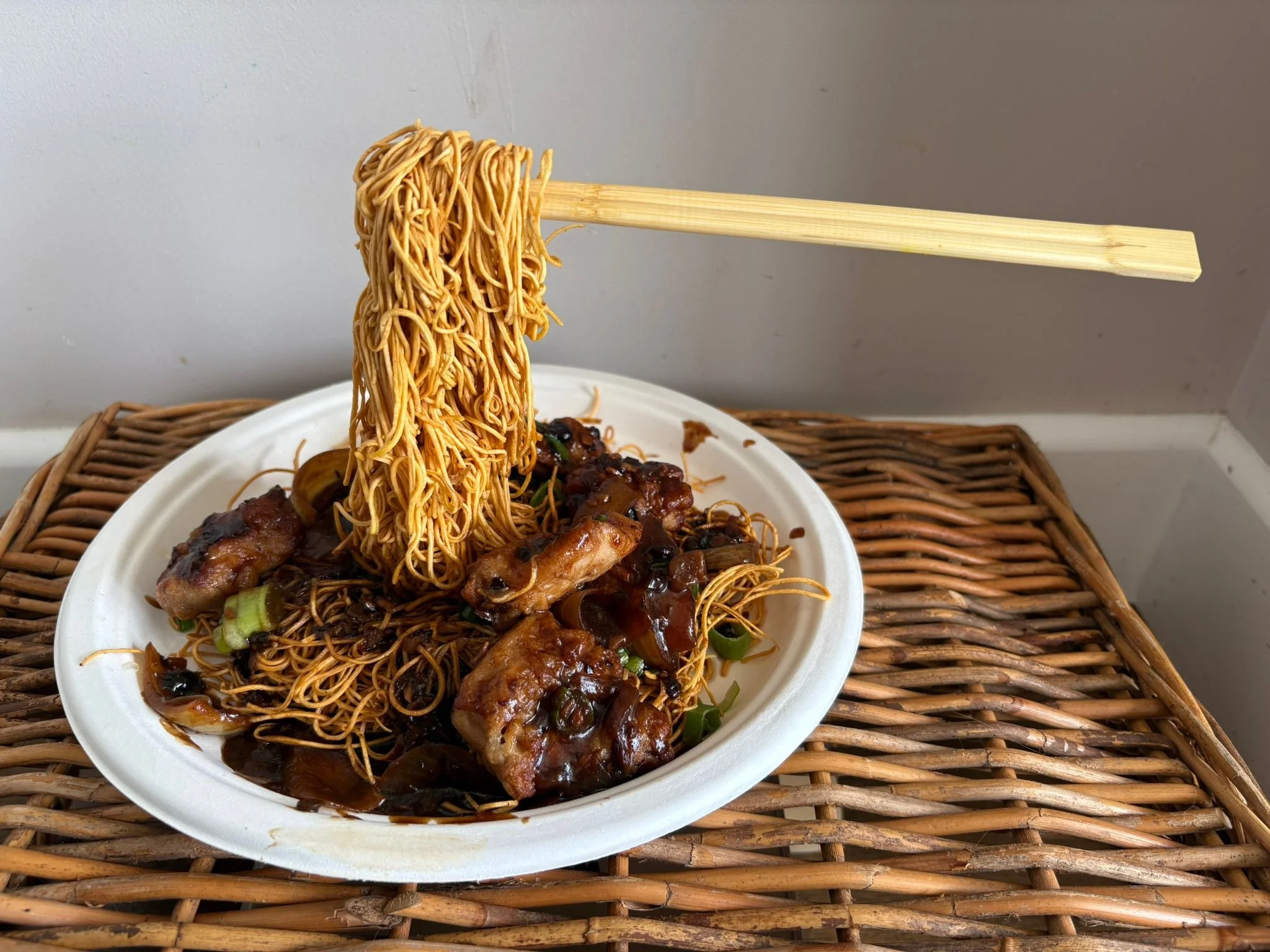 Magic Flying Chicken Noodles on a paper plate, being raised by chopsticks hanging in mid-air