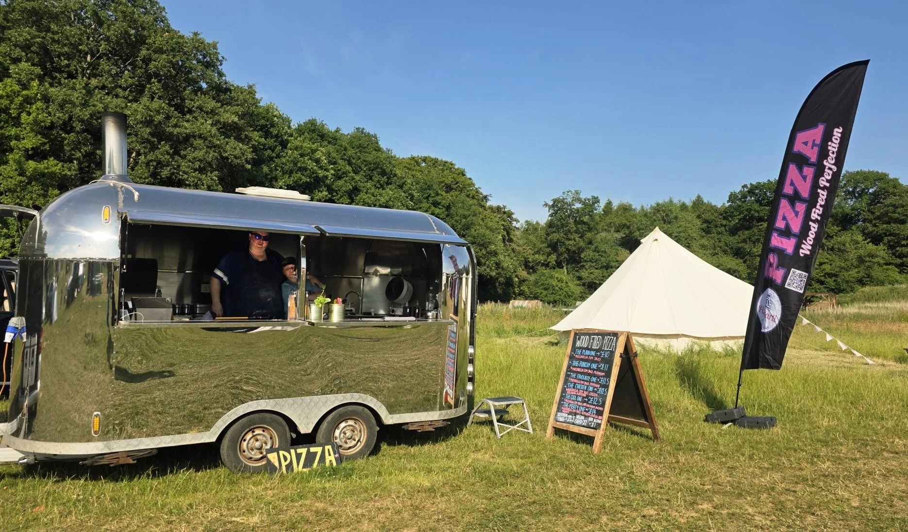 Pizzaarti Airstream style shiny trailer with menu board and Pizza flag