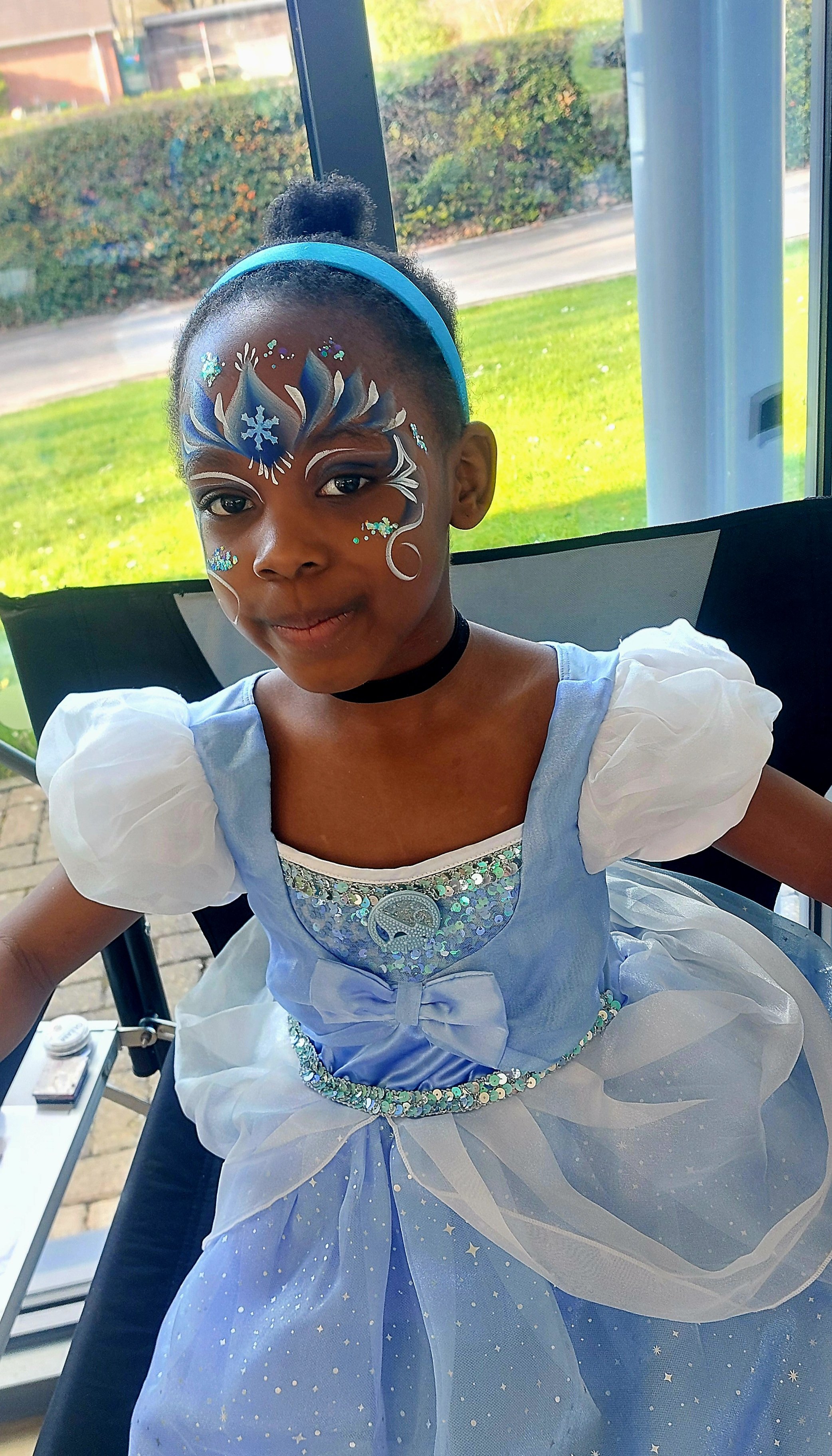 Girl in pale blue princess outfit, with Frozen themed face paint
