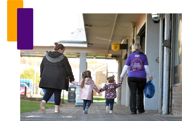 Mother and two girls walking down a street with a woman in a purple Home-Start t-shirt
