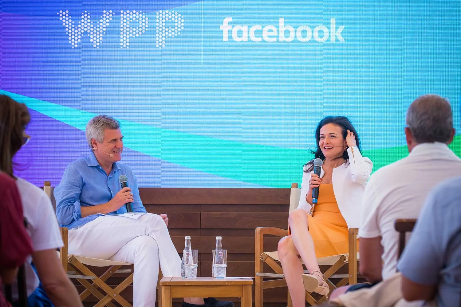 Panel discussion with a man and a woman sitting on stage with a large Facebook and WPP logo on the screen behind them, audience members in the foreground.