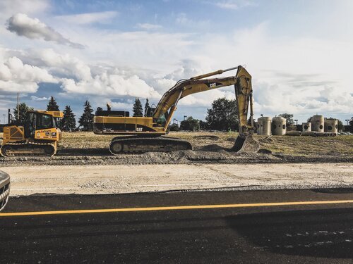 A construction side with a digger in the middle of it and a smaller vehicle on the left side..jpeg