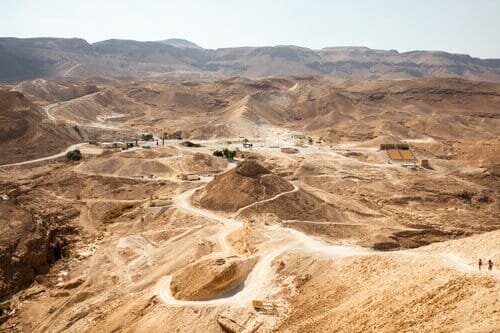 A mine site that looks similar to a desert and has mining vehicles standing in the centre..jpeg