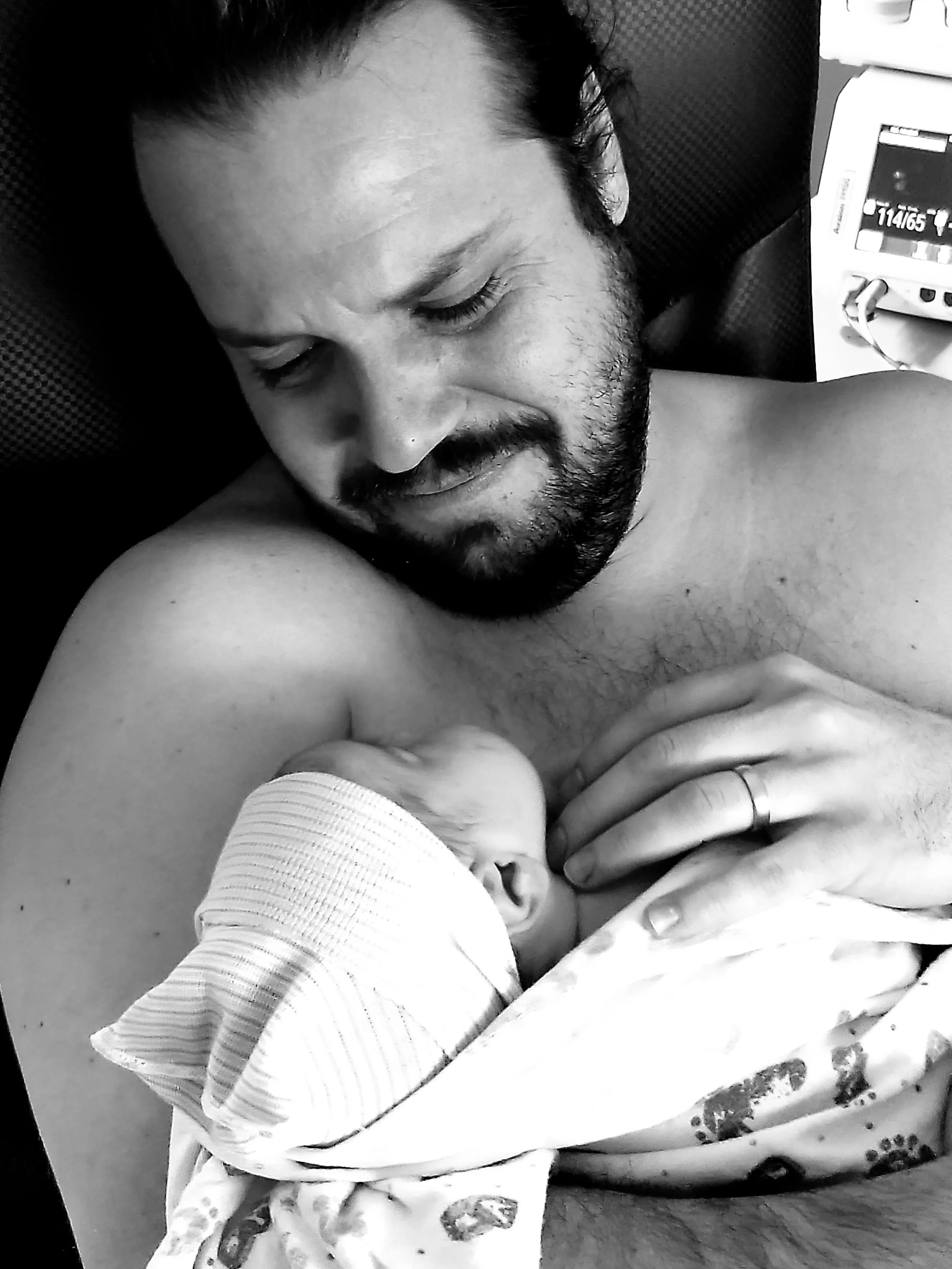 New dad admiring his new baby while doing skin to skin immediately after birth.
