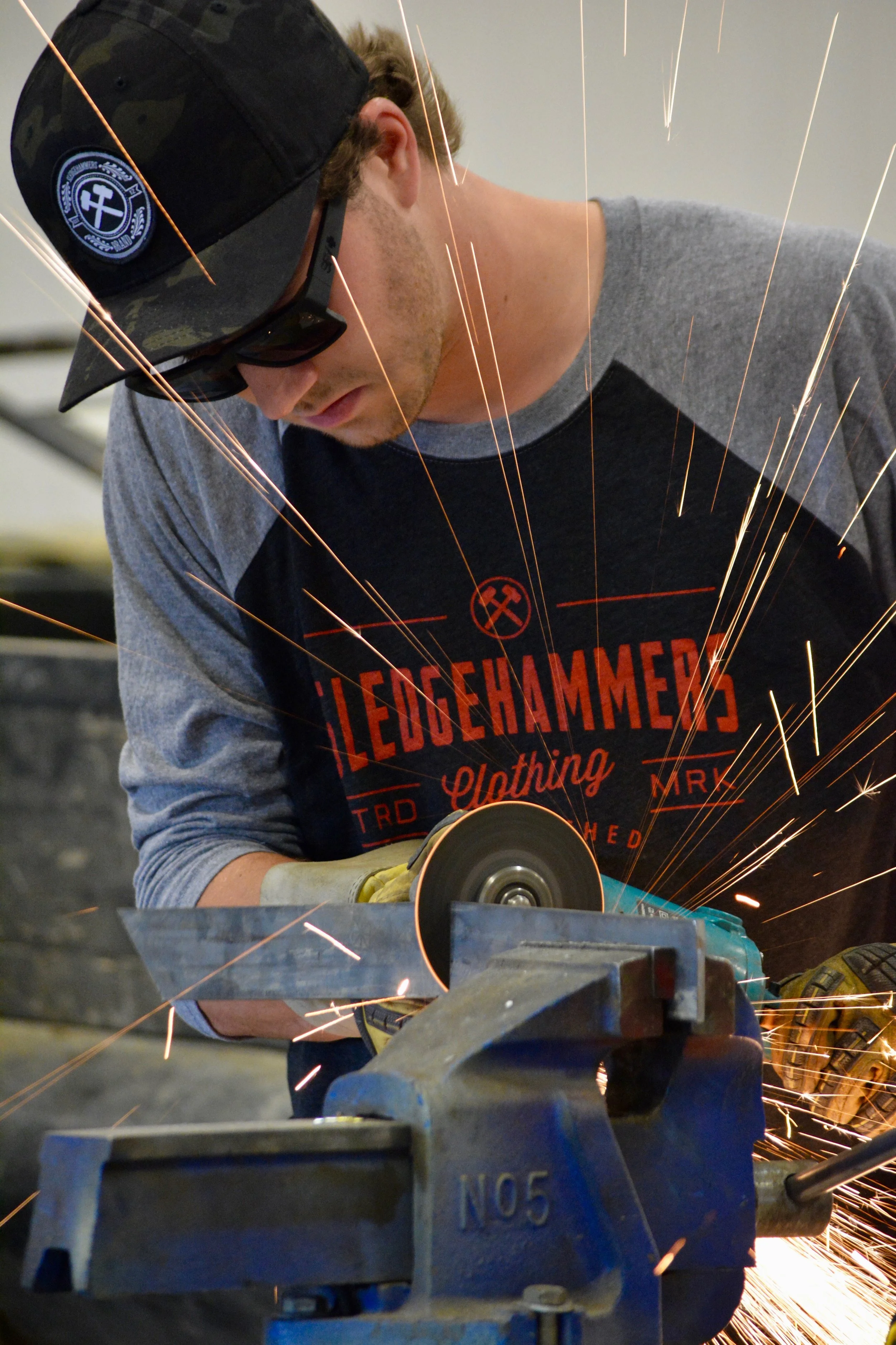 A man using a grinding machine creates sparks in a workshop.