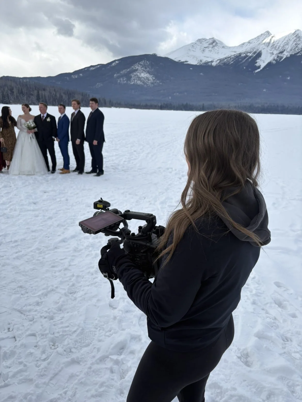 Filming a wedding party in the snow with mountains in the background