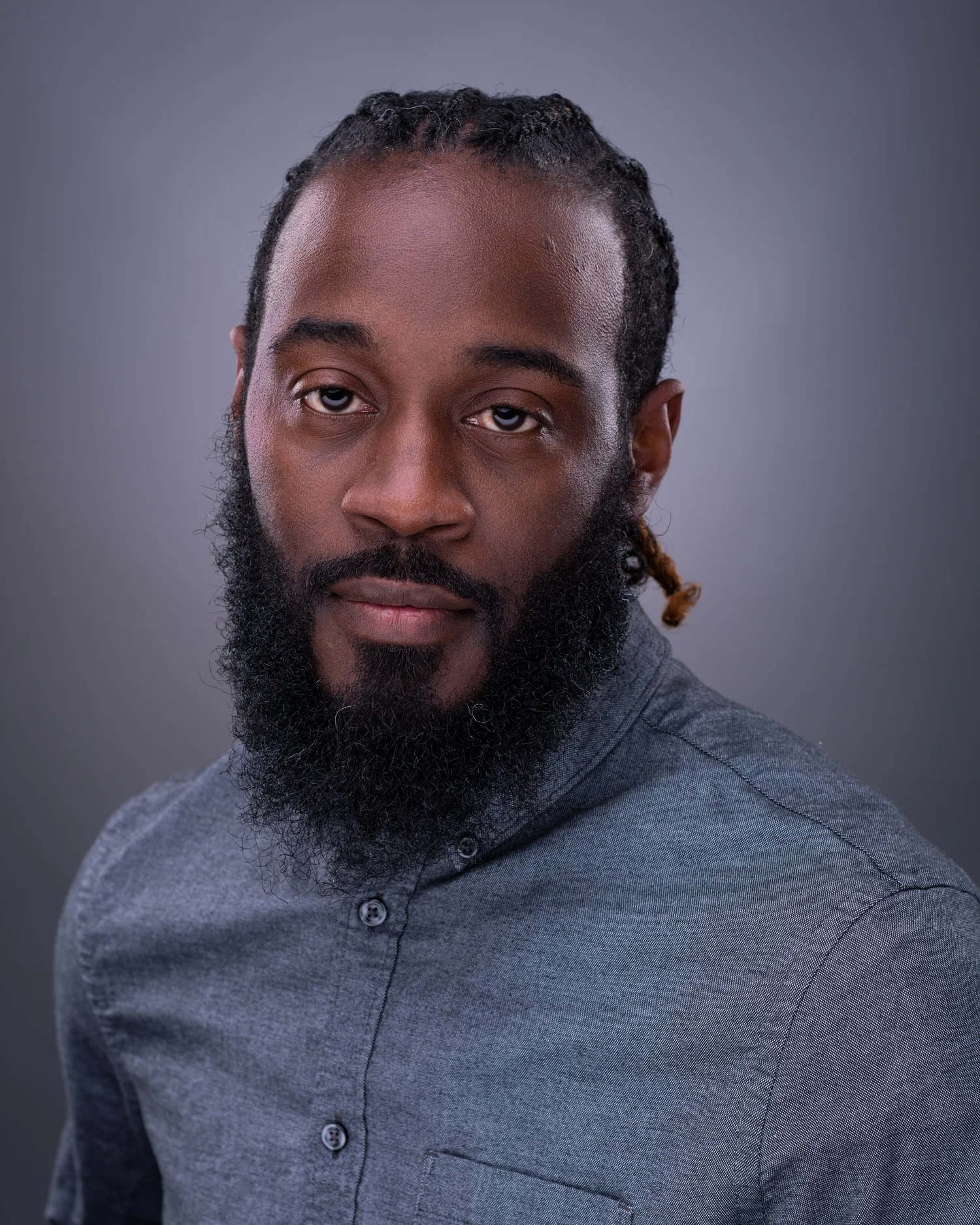 Studio headshot of a bearded man against a textured grey backdrop