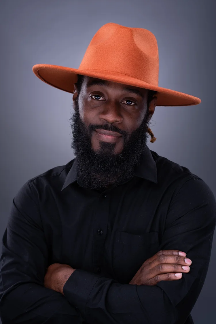Personal branding portrait of a man in an orange hat against a dark studio background