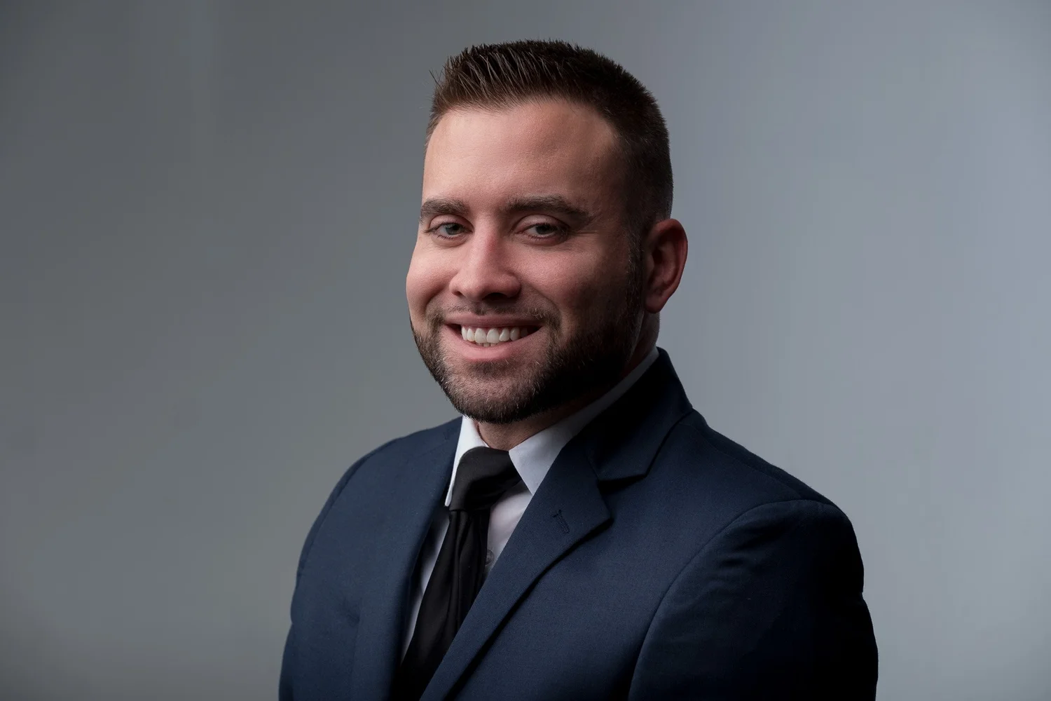 Smiling corporate headshot of a man in a navy suit