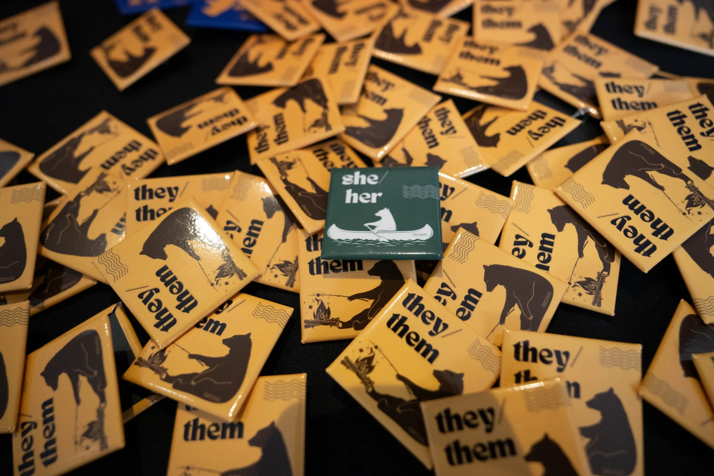 Two of four pronoun pins designed for Changemaker Skills Camp 2025