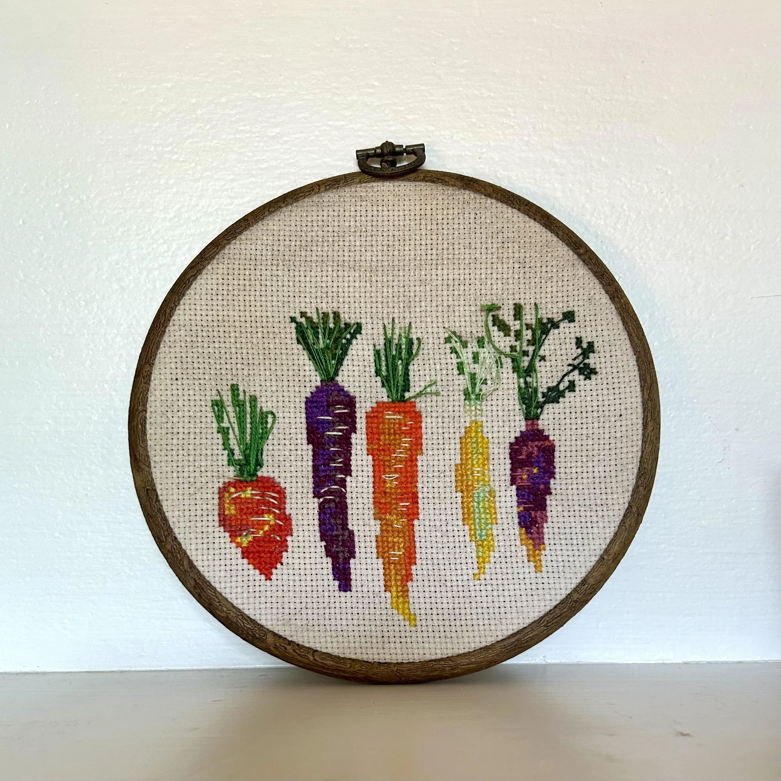 A cross-stitch design of rainbow carrots
