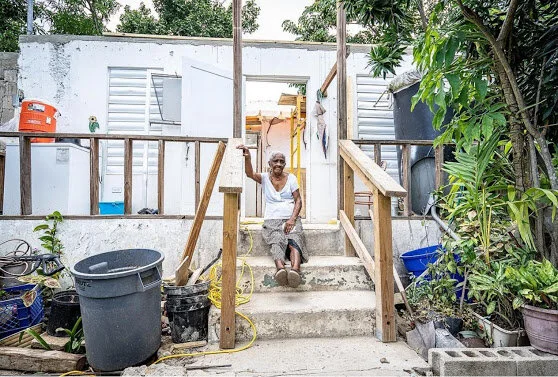A Viequense woman sits in front of what is left of her home, following Hurricane Irma and Maria.