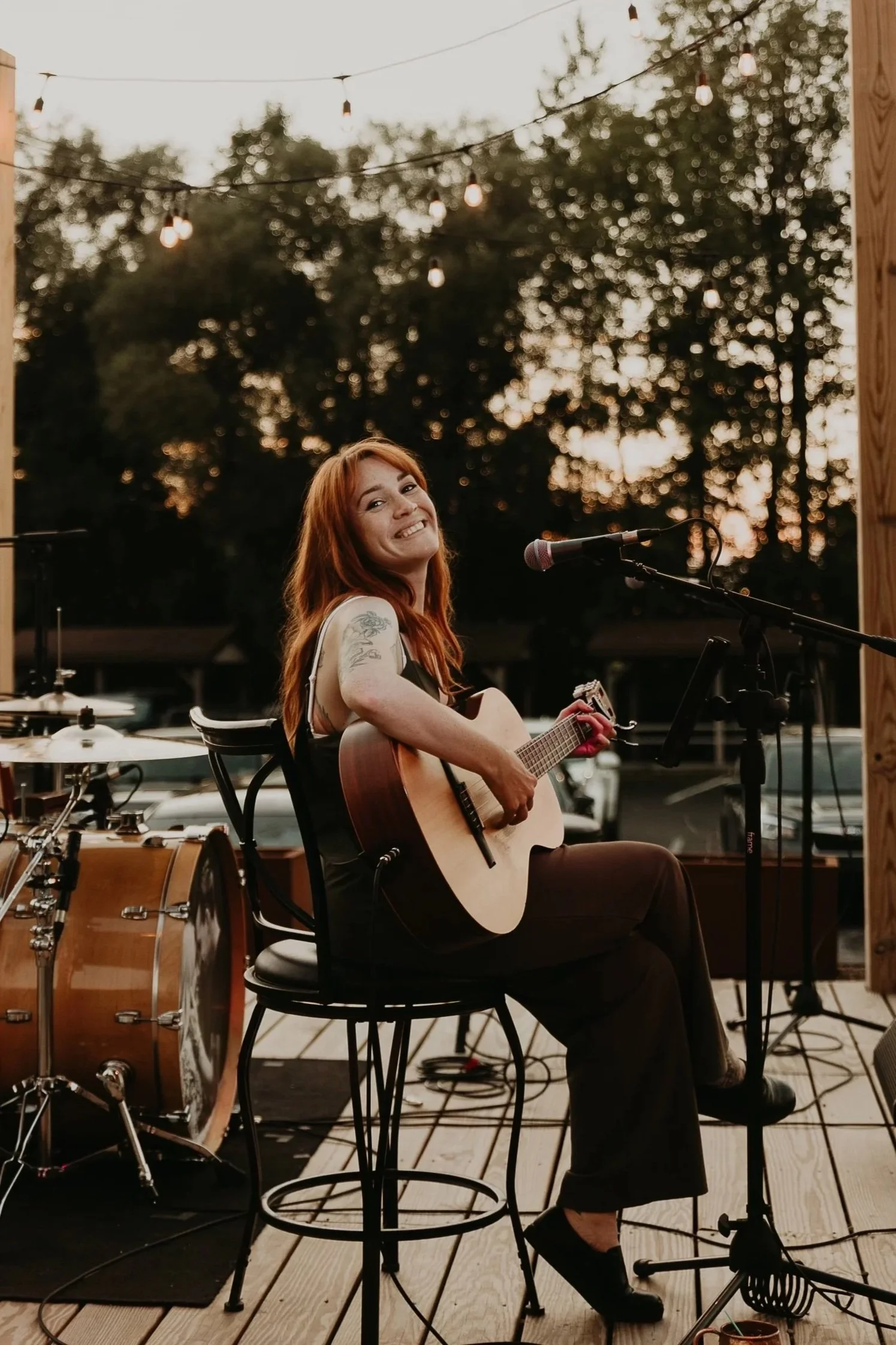 Brooke Surgener smiling performing solo at with acoustic guitar at local brewery in Erie PA