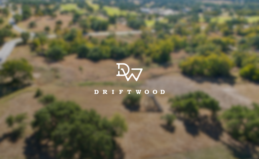 Aerial view of a landscape with trees and open land, blurred background, with a logo and the text 'Driftwood' in the center.