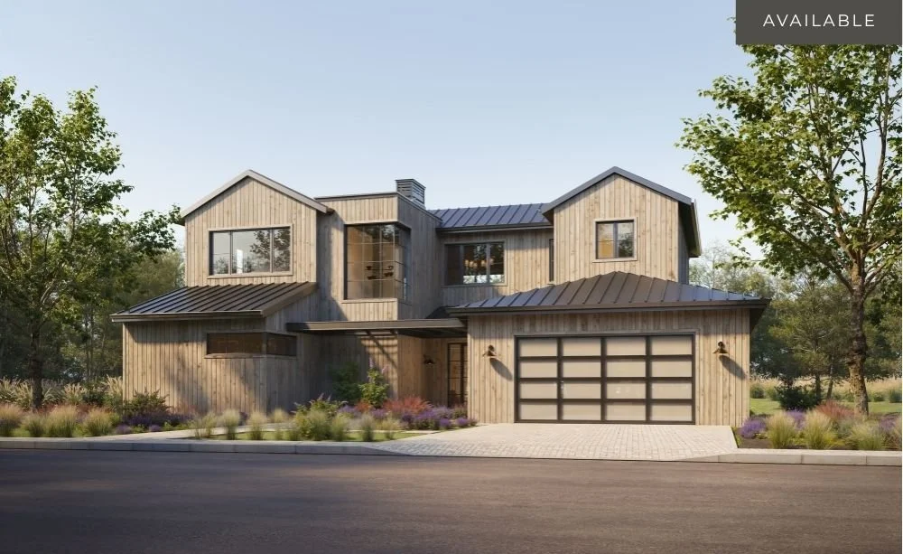 Modern two-story house with wooden exterior, metal roof, large windows, two-car garage, surrounded by trees and landscaping.