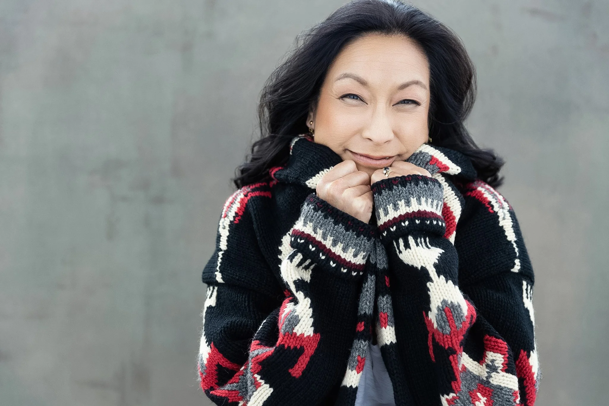 Woman in a bold patterned knit sweater against a gray wall, Nashville studio portrait by Judith Hill