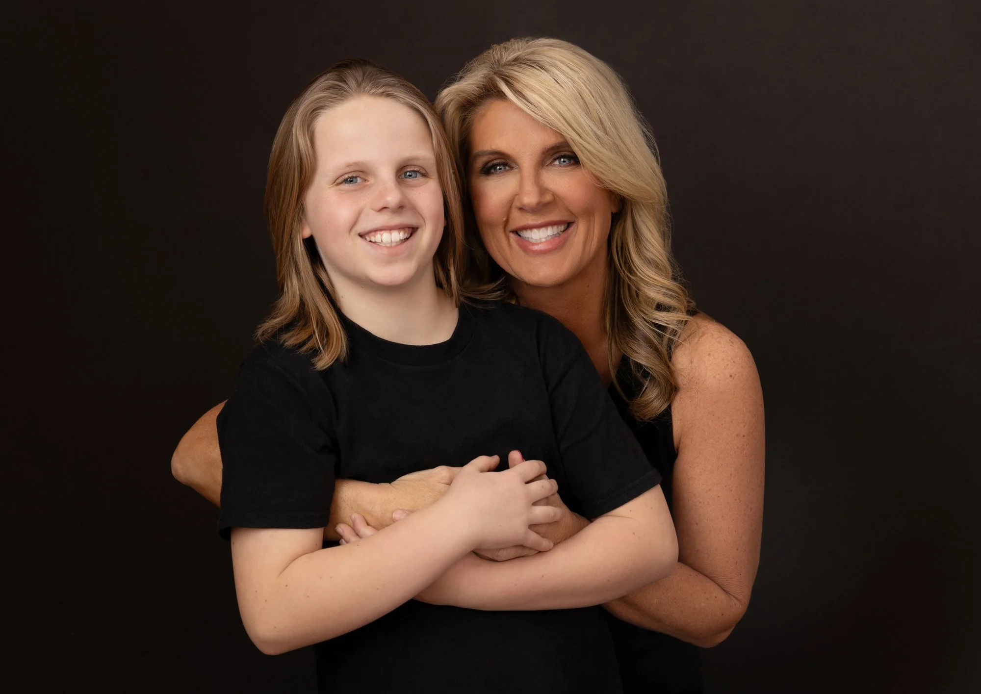  Mother and son smiling while embracing in a studio portrait, showing warmth and connection in a family photography session. 