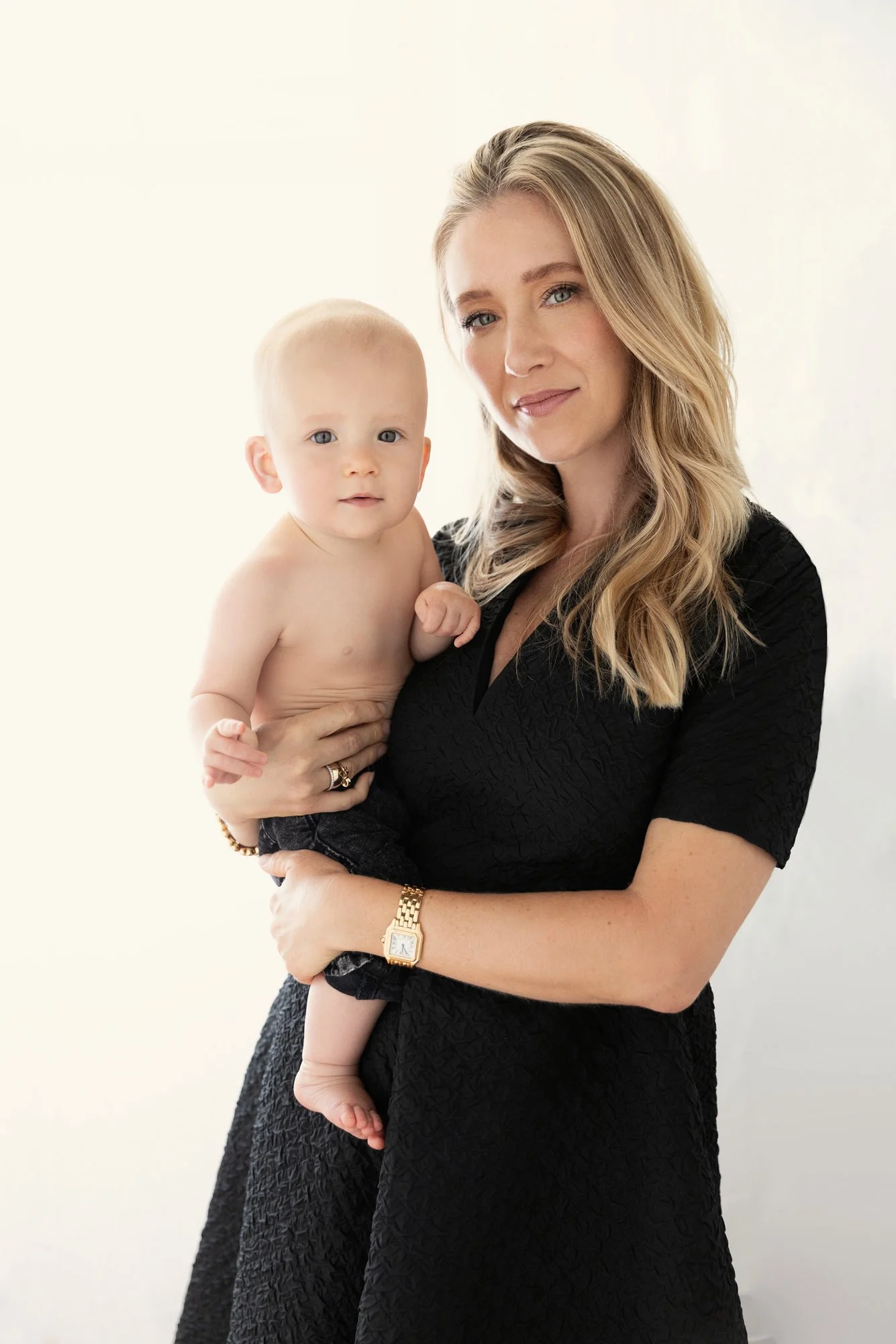  Mother holding a baby in soft natural light, highlighting nurturing connection and early motherhood in a timeless family portrait. 